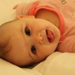 baby in pink shirt lying on bed
